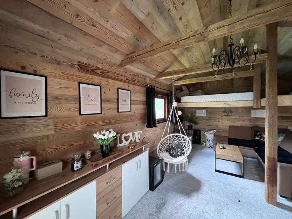 Dachgeschoss-Wohnraum mit Balkendecke und Wandverkleidung aus Altholz